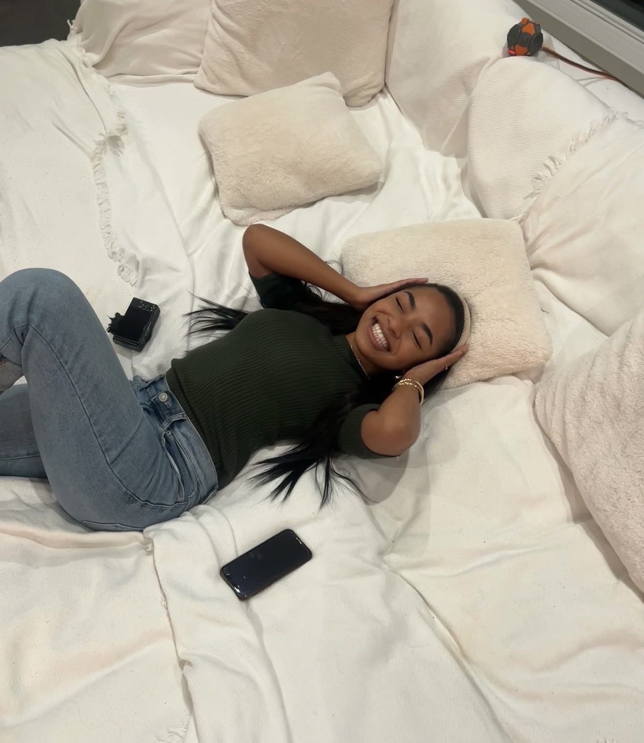 Ki’Loni Lee smiling on a cozy white couch.